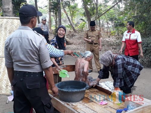mbah Rupik saat dimandikan oleh tetangga dan staf desa (foto : Gito / Jatim TIMES)