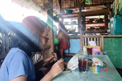 Pelanggan Rujak Syantik Tuplik saat menikmati rujak premium dari Desa Gesang Tempeh ini. (Foto: Pawitra/JatimTIMES)