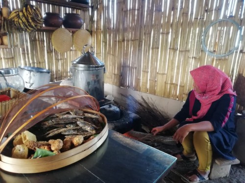 Suhartini saat membuat bara api di Kafe Ubi. (Foto: Irsya Richa/MalangTIMES)