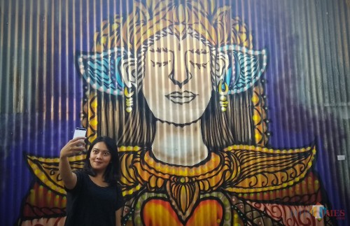 Pengunjung berfoto di depan karya berjudul Putri Agung dalam pameran tunggal seni rupa Buah Hati di Malang. (Foto: Nurlayla Ratri/MalangTIMES)