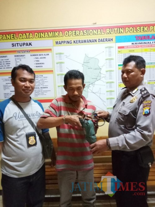Pelaku penganiayaan terhadap anak kandungnya saat diamankan di Mapolsek Perak. (Foto : Adi Rosul / JombangTIMES)
