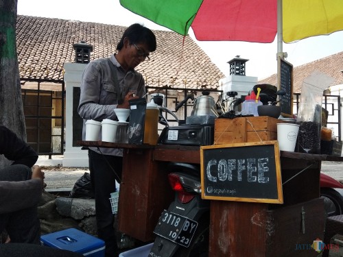 Achmad Yusuf saat meracik kopi yang dipesan pembeli. (eko Arif s /JatimTimes)