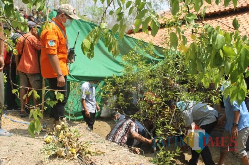 Petugas dibantu warga membongkar dan memindahkan makam Suryat Suyono setelah didemo warga sekitar. ( foto : Joko Pramono/Jatim Times)