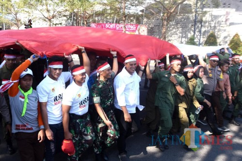 Walikota Kediri Abdullah Abu Bakar bersama Forkopimda dan ribuan pelajar di Kota Kediri mengarak bendera berukuran raksasa. (eko Arif s /JatimTimes)