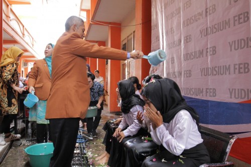 Dekan Fakultas Ekonomi dan Bisnis Unikama, Drs. Sulistyo, M.Ak mbk saat menyiramkan air bunga kepada mahasiswa dalam prosesi yudisium (foto: FEB Unikama for MalangTIMES)