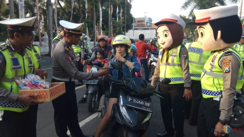 Petugas memberikan bunga dan cokelat pada salah seorang pengendara
