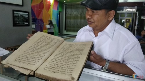 Pengelola Perpustakaan Sejarah dan Budaya Puspa Lulut, Lulut Edi Santoso, menunjukkan salah satu naskah kuno yang dipamerkan di Perpustakaan Umum Kota Malang. (Foto: Nurlayla Ratri/MalangTIMES)