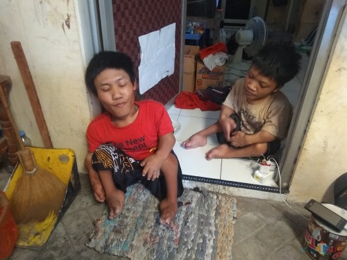 Hendra Kristianto (baju merah) bersama adiknya dirumah kost berukuran 3x3 meter. (eko Arif s /JatimTimes)