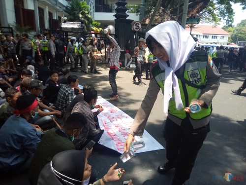 Polwan yang terlihat tengah membagikan air minun pada peserta aksi (Anggara Sudiongko/MalangTIMES)