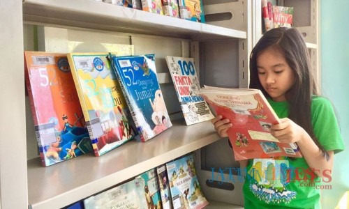Salah satu anak sedang membaca buku di di Taman Baca Masyarakat (TBM) Taman Bondas, Jl Sultan Agung, Kecamatan Batu. (Foto: Irsya Richa/MalangTIMES)