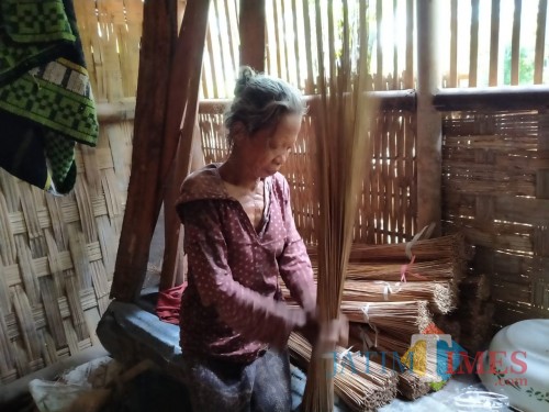 Mbah Sumirah saat membuat sapu lidi di rumahnya (foto : Gito / Jatim TIMES)