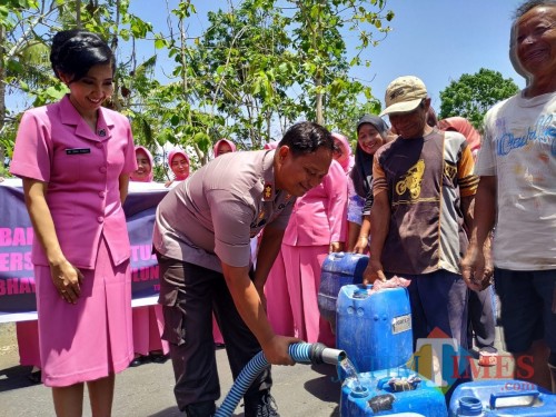 AKBP Eva Guna Pandia saat menuangkan air dari tangki ke tempat penampungan yang disiapkan warga Foto: Anang Basso / Tulungagung TIMES