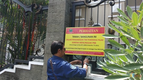 Pemasangan papan peringatan di rumah yang menunggak PBB oleh tim operasi gabungan BP2D Kota Malang. (Pipit Anggraeni/MalangTIMES).