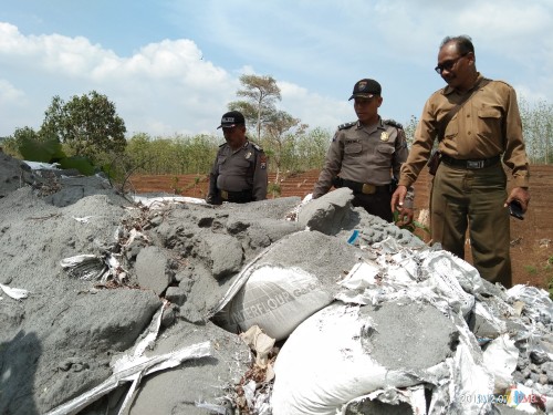 Anggota Polsek Kalangbret dan Pegawai Perhutani memeriksa tumpukan material yang diduga limbah B3 (foto: Joko Pramono/ JatimTIMES)