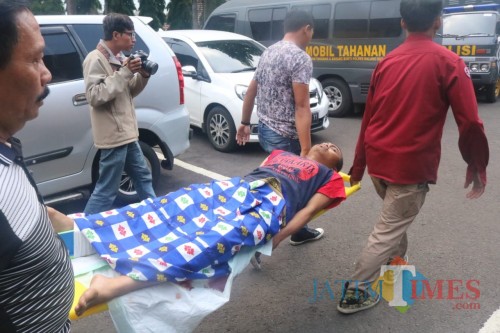 Kondisi tersangka Nur Kholis saat ditandu oleh petugas kepolisian di Polresta Malang Kota. (Arifina Cahyanti Firdausi/MalangTIMES)