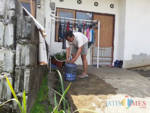 Salah satu warga yang terdampak air mati saat sedang mengisi air dari fasilitas perumahan. (Arifina Cahyanti Firdausi/MalangTIMES)