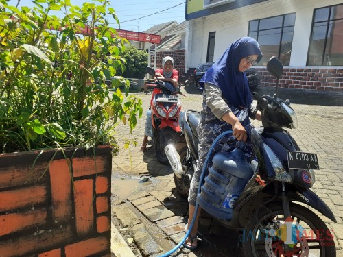 Warga perumahan BTU, Kelurahan Madyopuro, Kecamatan Kedungkandang yang bolak-balik mengambil air dari tandon fasilitas perumahan (Arifina Cahyanti Firdausi/MalangTIMES)