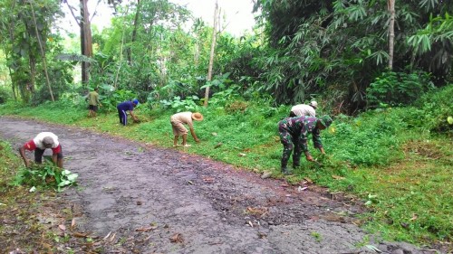 Sertu Suyanto bergotong royong bersama warga, bersihkan rumput dan sampah.