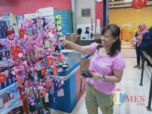 Belanja hepi, nampak salah seorang customer Graha Bangunan senang dapat hadiah pohon angpao.(Foto : Aunur Rofiq/BlitarTIMES)