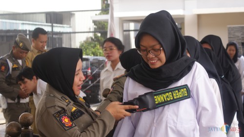 Salah seorang peserta diperiksa menggunakan metal detektor oleh Satpol PP sebelum masuk ruang ujian (Joko Pramono for JatimTIMES)