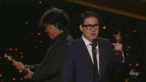 Sutradara Parasite Bong Joon Ho (di belakang Jin Won Han) kedapatan cengar-cengir menatap piala Oscar. (Foto: screenshot video)