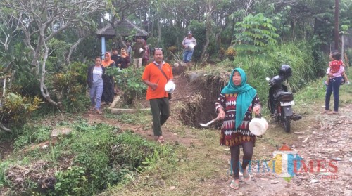 Para warga saat memukul peralatan dapur guna mencari keberadaan korban yang dikabarkan hanyut terbawa arus sungai sesaat setelah jatuh ke selokan (Foto : Ashaq Lupito / MalangTIMES)