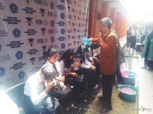 Dekan FEB, Drs Sulistyo saat melakukan siraman kepada mahasiswa FEB Unikama yang telah lulus (Anggara Sudiongko/MalangTIMES)