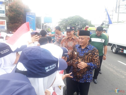 Bupati Malang H.M. Sanusi yang didampingi oleh Ketua DPRD Kabupaten Malang Didik Gatot Subroto (memakai topi bertanda bendera merah putih) saat menyalami siswa-siswi pada acara Gema Desa di Singosari, Kamis (20/2/2020) . (Foto: Tubagus Achmad/MalangTIMES)