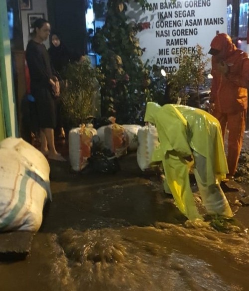 Petugas saat memberikan penahan di area luapan air Jalan Diponegoro No. 7 RT 01 RW 02 Dusun Gondang Desa Tulungrejo Kecamatan Bumiaji, semalam. (Foto: istimewa)