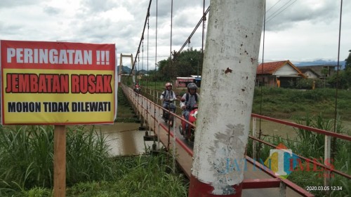 nekat, sejumlah pelajar dan masyarakat tetap melewati jemabtan itu meski sudah ada papan larangan untuk melewati jembatan itu (Joko Pramono/ JatimTIMES)