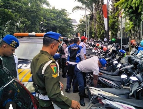 Petugas operasi gabungan saat gembosi kendaraan roda dua yang parkir di area terlarang di Jl. Veteran (Istimewa).