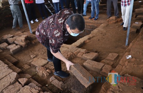 Wakil MPR RI Ahmad Bashara saat memegang batu bata temuan situs di Dusun Pendem, Desa Pendem, Kecamatan Junrejo, Minggu (15/3/2020).