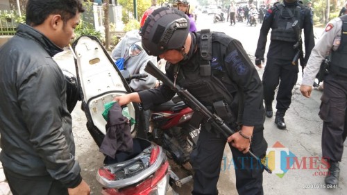 petugas saat memeriksa barang bawaan peserta harlah di perempatan Tanggung, Kecamatan Boyolangu (Joko Pramono for Jatim Times)