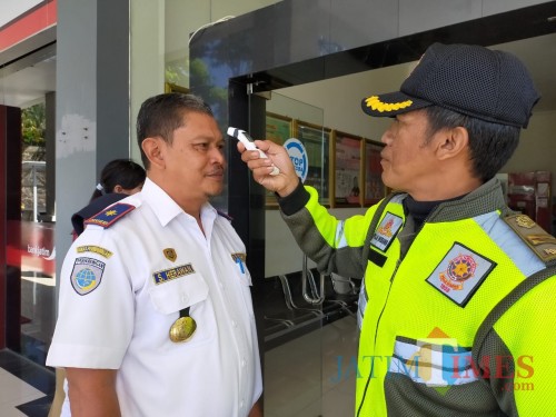 Salah satu petugas sedang memeriksa kepala Dinas Perhubungan di Balai Kota Among Tani, Senin (16/3/2020). (Foto: Muklas/JatimTIMES)