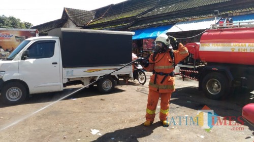 Salah satu petugas Pemadam Kebakaran Kota Batu menyemprot disinfektan di Pasar Besar Kota Batu, Jumat (20/3/2020). (Foto: Irsya Richa/MalangTIMES)