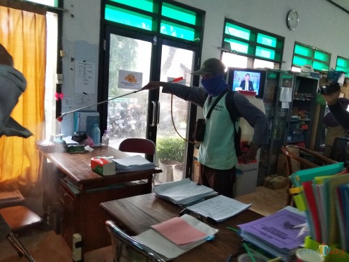 Petugas menyemprotkan disinfektan di lingkungan kerja DLHKP. (Eko Arif S /JatimTIMES)
