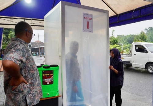 Salah satu masyarakat saat menjajal bilik disinfektan di Desa Sumbergondo Kecamatan Bumiaji. (Foto: istimewa)