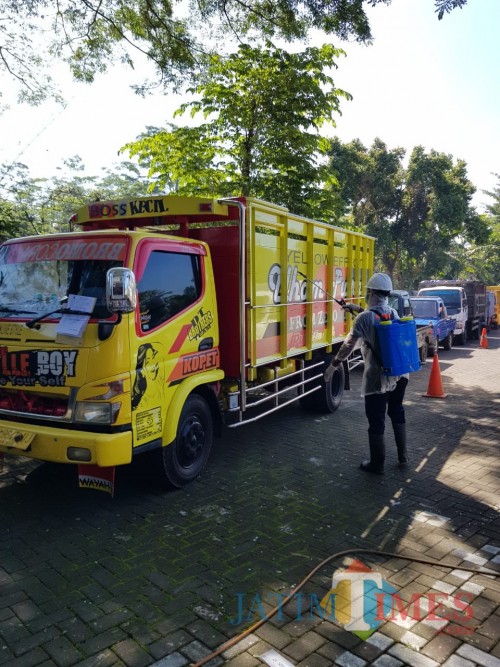 Para petugas Dishub Kabupaten Malang melakukan penyemprotan disinfektan ke kendaraan yang akan diuji kir. (dd nana)