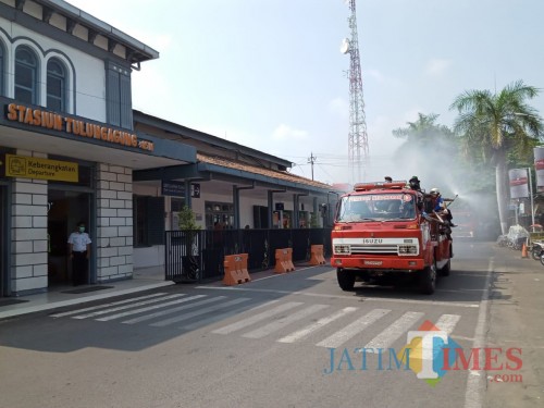 mobil damkar sedang melakukan penyemprotan di jalan protokol, seperti di depan Stasiun Tulungagung. (Joko Pramono for Jatim Times)