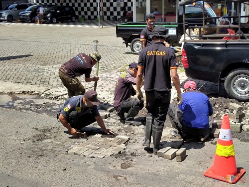 Para personel satgas DPUPRPKP saat melakukan penambalan lubang jalan di Jalan Candi Mendut. (Anggara Sudiongko/MalangTIMES)