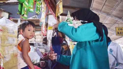 Ferry Silviana Abu Bakar Ketua PKK Kota Kediri ini menyerahkan langsung masker kepada tukang becak, penjual maupun pembeli di Pasar Bandar. (Foto: Ist)