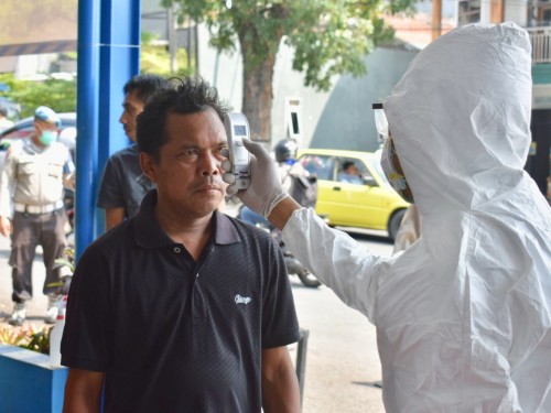 Petugas saat memeriksa suhu tubuh pengendara di pos pemantauan di simpang tiga Pendem, Kecamatan Junrejo. (Foto: istimewa)