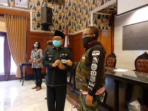 Wali Kota Malang Sutiaji (berkopyah) saat menyerahkan kartu bantuan sosial secara simbolis kepada warga terdampak Covid-19, Rabu (29/4). (Arifina Cahyanti Firdausi/MalangTIMES).