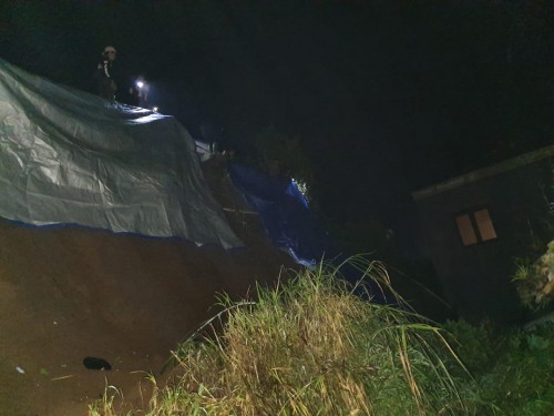 Petugas saat melakukan penutupan terpal pada tebing yang longsor Desa Sumber Brantas, Kecamatan Bumiaji, Jumat (8/5/2020). (Foto: istimewa)