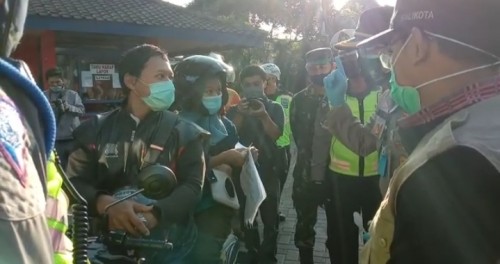 Erna bersama sang suami, warga asal Sidoarjo yang hendak masuk Kota Malang, diminta petugas untuk menunggu di pos check point batas kota di Bale Arjosari. (Ist)