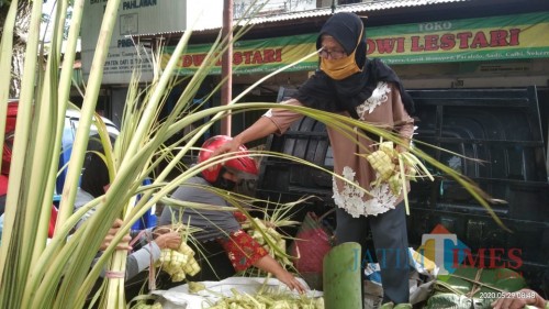 Sulastri, penjual ketupat saat melayani pembeli di pasar Ngempalak (Joko Pramono for Jatim TIMES)