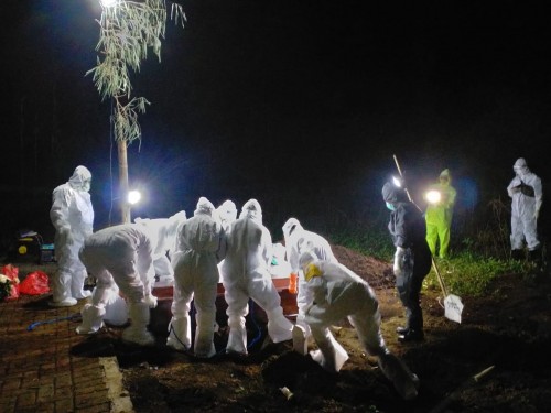 Petugas saat memakamkan pasien meninggal positif covid-10 beberapa saat lalu di Desa Giripurno, Kecamatan Bumiaji. (Foto: istimewa)