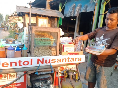 Lutfan menyiapkan buku-buku yang akan dibawanya berjualan pentol keliling. (Foto : Adi Rosul / JombangTIMES)