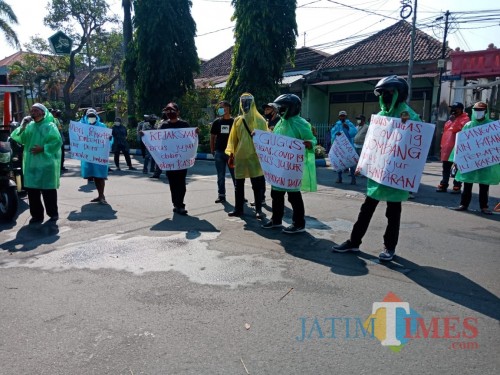 Massa aksi Projo kenakan jas hujan kresek saat berunjuk rasa di depan DPRD Jombang. (Foto: Adi Rosul/ JombangTIMES)