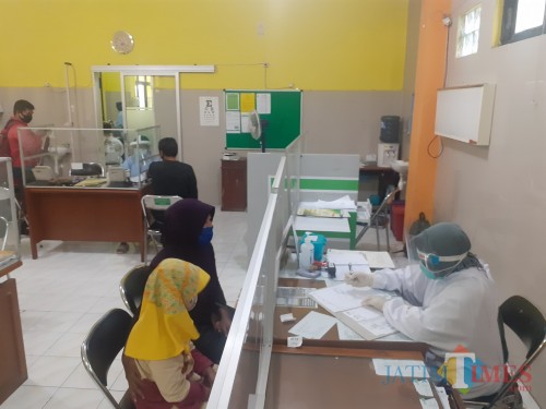 Proses pelayanan pemeriksaan kesehatan di Puskesmas Kedungkandang yang sudah dilengkapi dengan penyekat. (Arifina Cahyanti Firdausi/MalangTIMES).